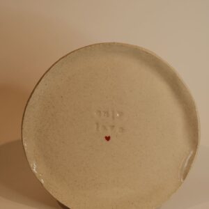 Petite assiette avec un cœur rouge au milieu et "Only Love" gravé.